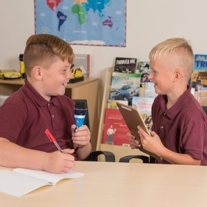 Two boys in classroom speaking to each other