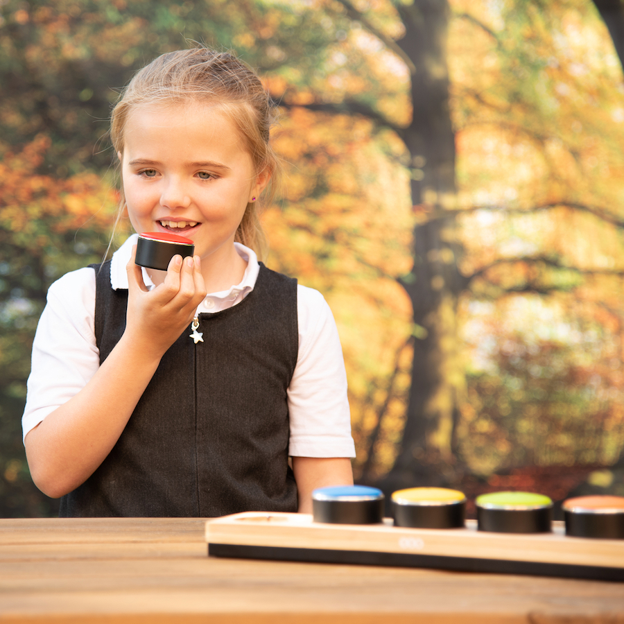 Young girl talking into a small hand held machine to record her voice
